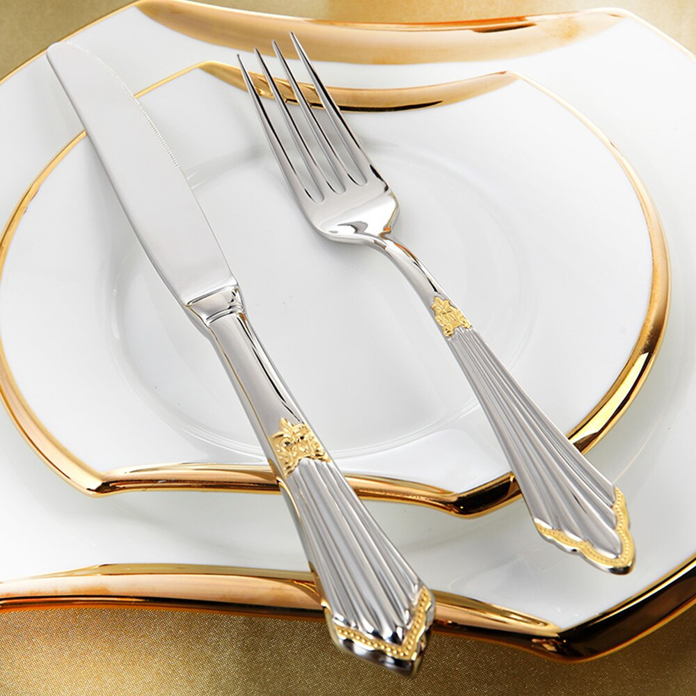 Close-up of polished gold stainless steel cutlery set, showing fork, knife, spoon; luxury dining essential.