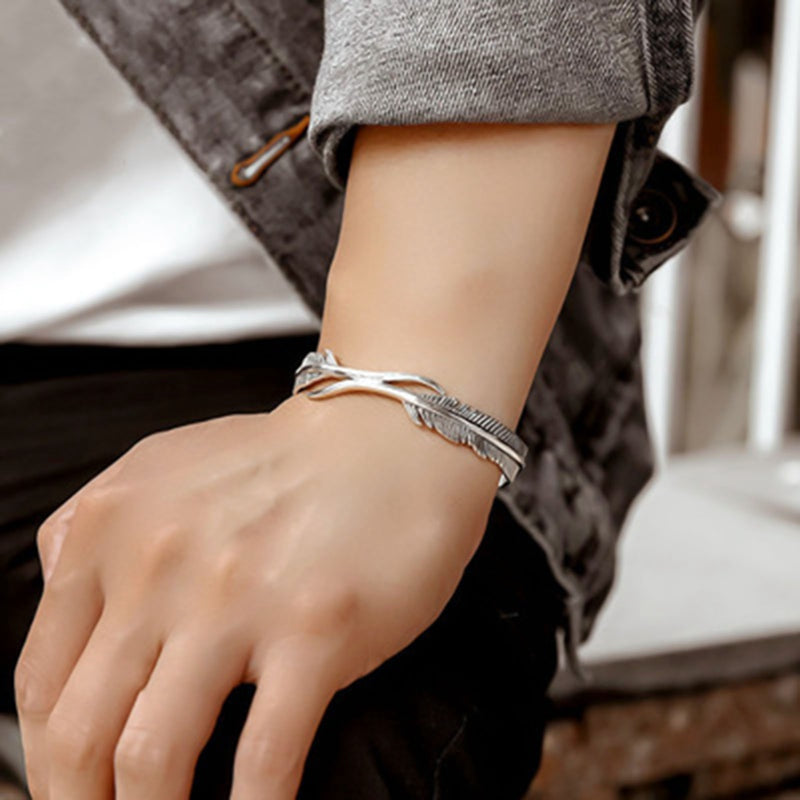 Delicate silver feather charm bracelet, adjustable fit. Elegant women's fashion accessory.