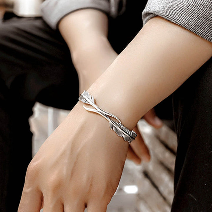 Close-up of an adjustable silver bracelet with intricate feather charms, ideal for delicate jewelry lovers.