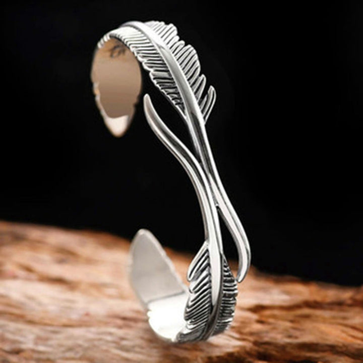 Woman's wrist wearing an adjustable silver feather charm bracelet, a stylish everyday accessory.