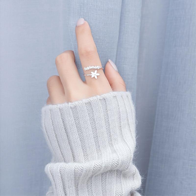Close-up of a women's adjustable sterling silver ring with delicate enamel wildflowers. Floral, nature-inspired design.