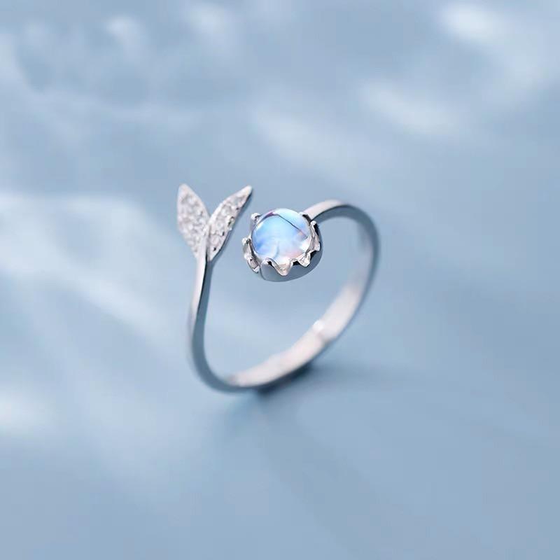 Adjustable women's dolphin tail ring crafted in silver with a vibrant blue zirconia stone. Ocean jewelry.
