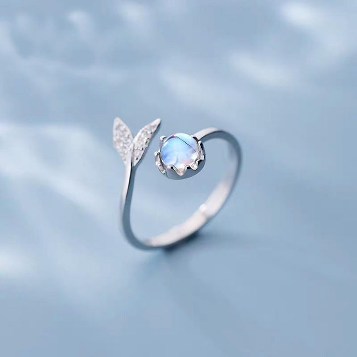 Adjustable women's dolphin tail ring crafted in silver with a vibrant blue zirconia stone. Ocean jewelry.