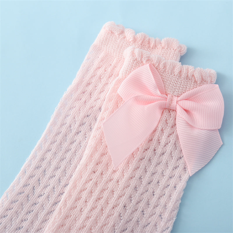 Texture shot of super soft baby cotton socks holding a beautiful large bow, emphasizes comfort for delicate newborn skin.