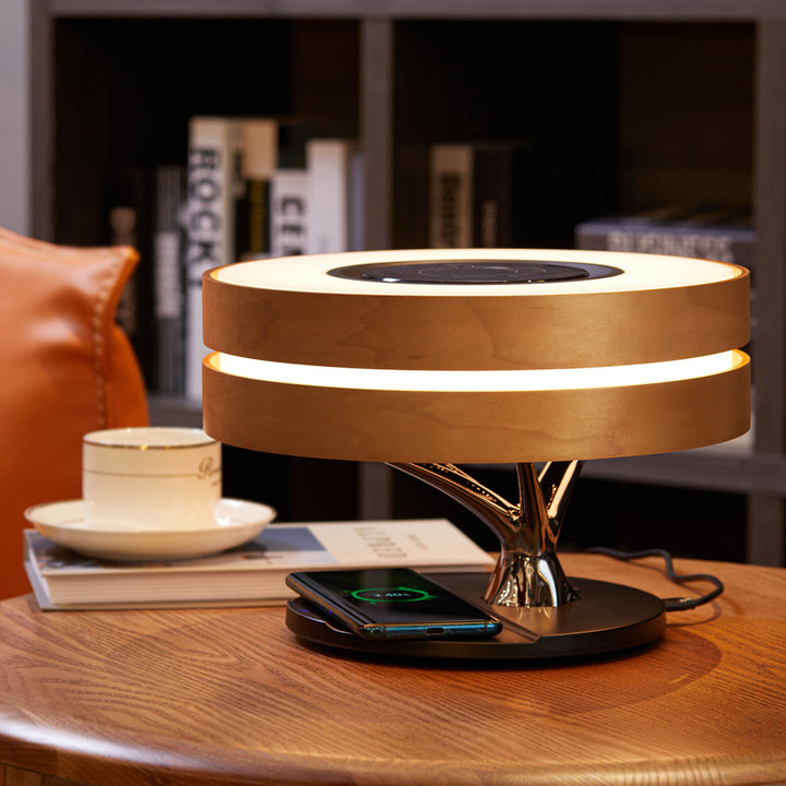 Close-up of AmbiLuxe wireless charging pad and Bluetooth speaker on a modern desk lamp, ambient lighting.