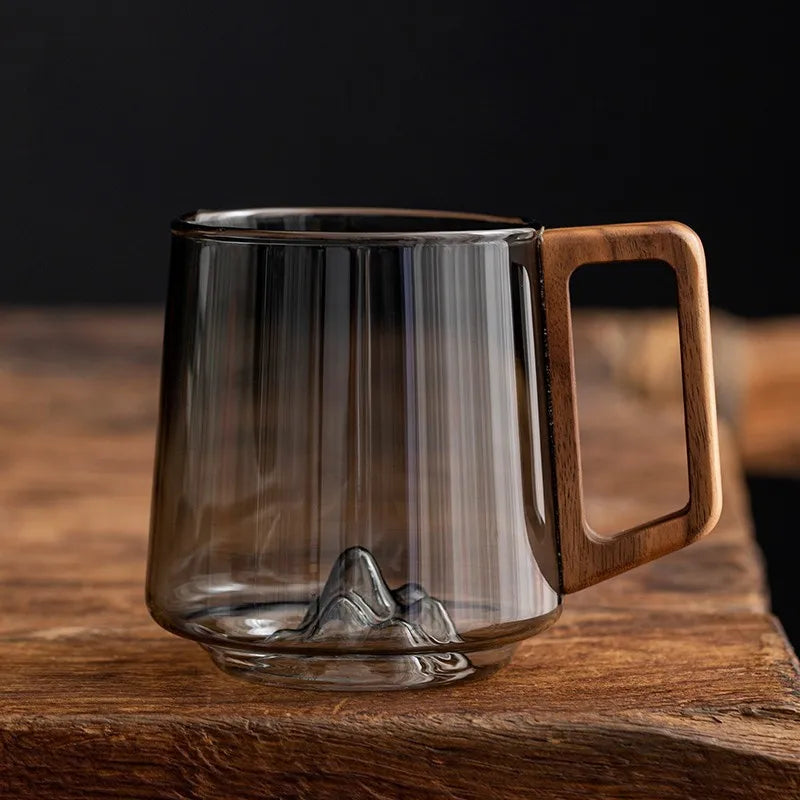Artistic borosilicate glass mug with unique mountain base and ergonomic wooden handle. Perfect for coffee or tea.