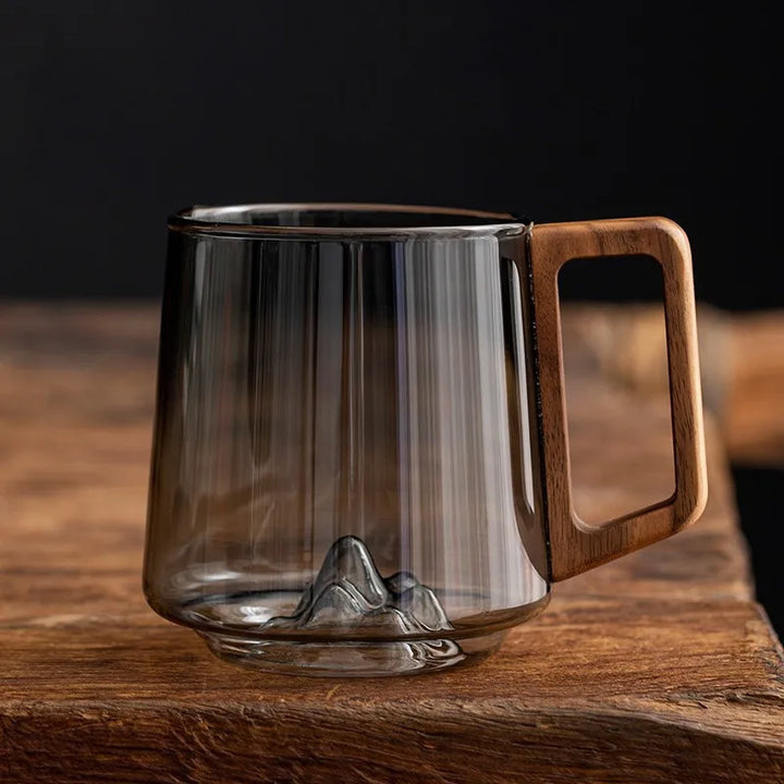 Artistic borosilicate glass mug with unique mountain base and ergonomic wooden handle. Perfect for coffee or tea.