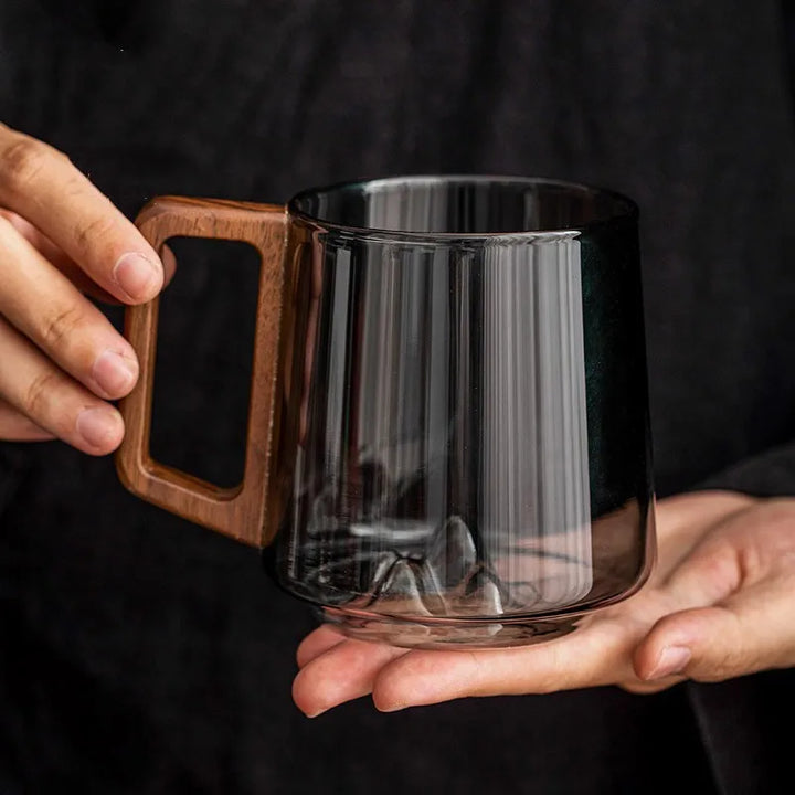 Clear glass mug with an intricate mountain base and a smooth wooden handle. Ideal for hot beverages and a unique gift.
