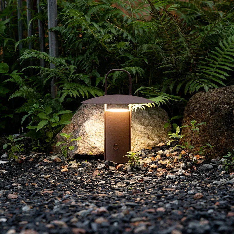 AuraPorto rechargeable outdoor lantern illuminating a patio at dusk, warm LED glow.