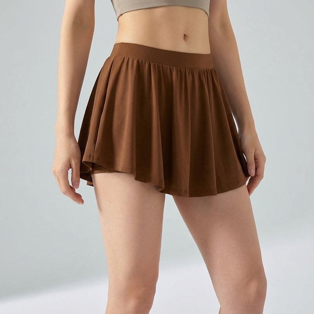 Dynamic shot of women's Ava sporty mini skirt in navy, highlighting its flexibility and built-in shorts.