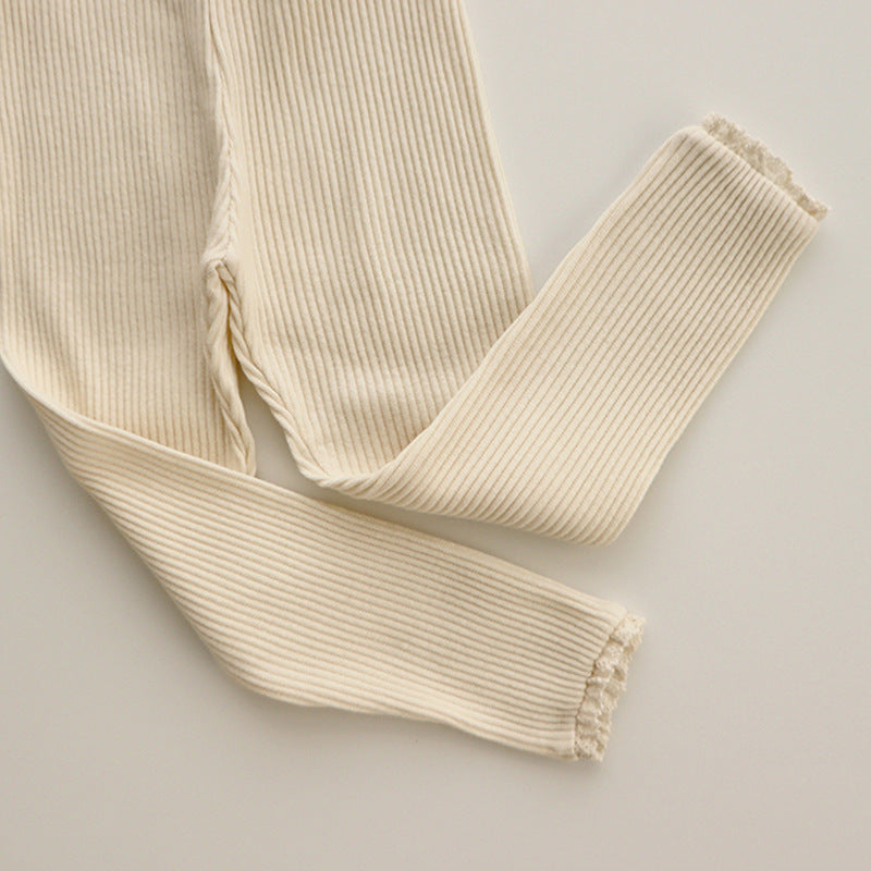Close-up of ribbed baby leggings with intricate white lace trim for girls, showcasing the soft cotton knit and detailing