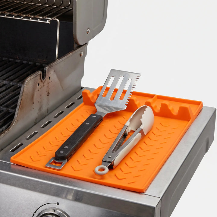 Silicone utensil rest with drip tray for grill tools, preventing messes on kitchen counters & BBQ areas.