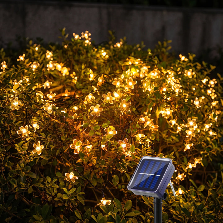 Blossom solar outdoor string lights illuminating a garden path. Waterproof LED flower lights for patio decor.