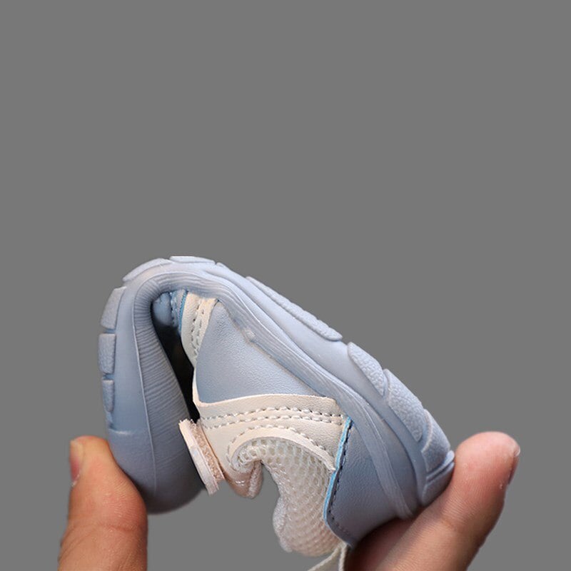 Baby wearing blue FlexiToes barefoot sneakers, flexible for natural first steps & healthy feet.