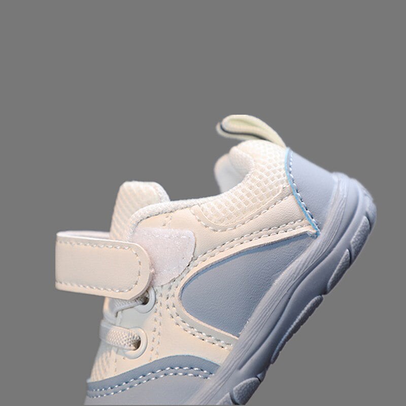 Infant in beige FlexiToes barefoot sneakers, anti-slip and supportive for healthy foot development.