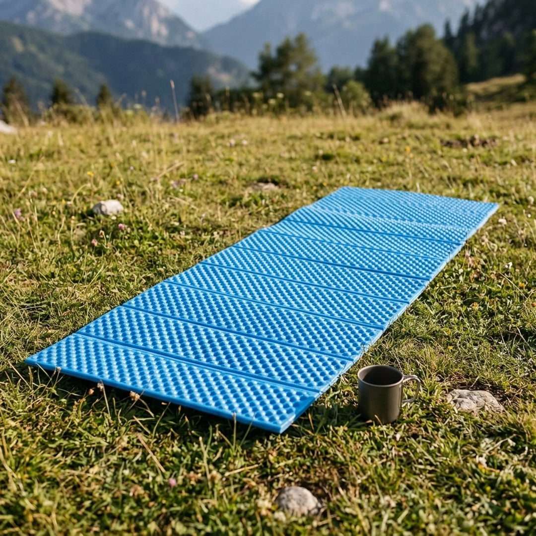 Blue foldable closed-cell camping mat for outdoor sleeping.
