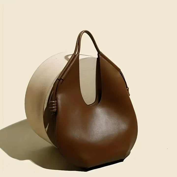 Front view of a chic obsidian oversized tote bag, minimalist design in durable vegan leather.