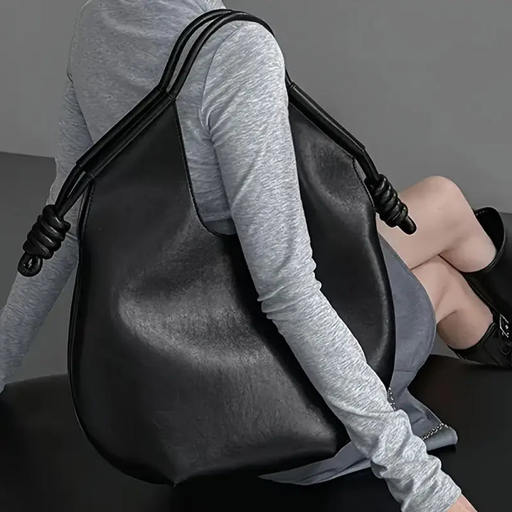 Woman carrying a stylish oversized vegan leather shoulder bag, perfect for a modern look.