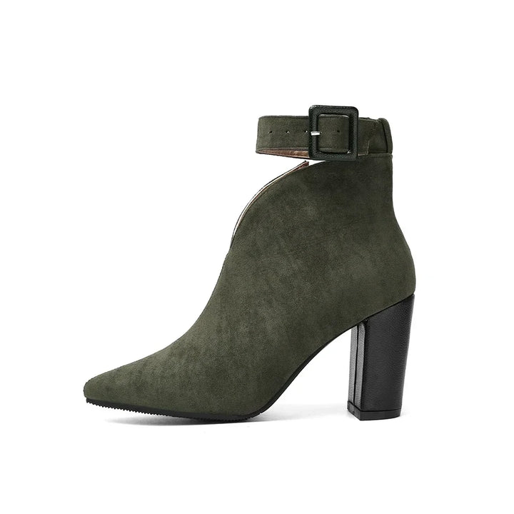 Close-up of stylish buckle on women's chic ankle boots with pointed toe & block heel.