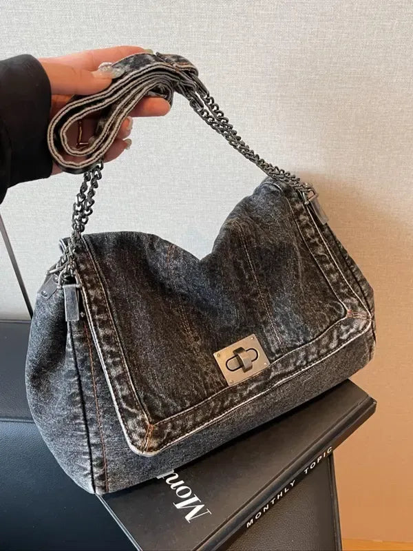 Chic women's dark denim shoulder bag with elegant chain strap. Versatile handbag for casual or dressed-up looks.