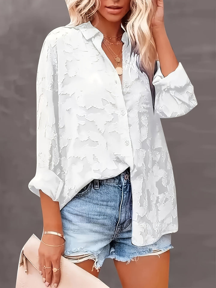 Close-up of a women's jacquard V-neck blouse, highlighting luxurious fabric & loose fit for elegant style.