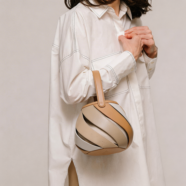 Beige spiral cage bucket handbag for women. A sophisticated top handle fashion accessory with elegant design.