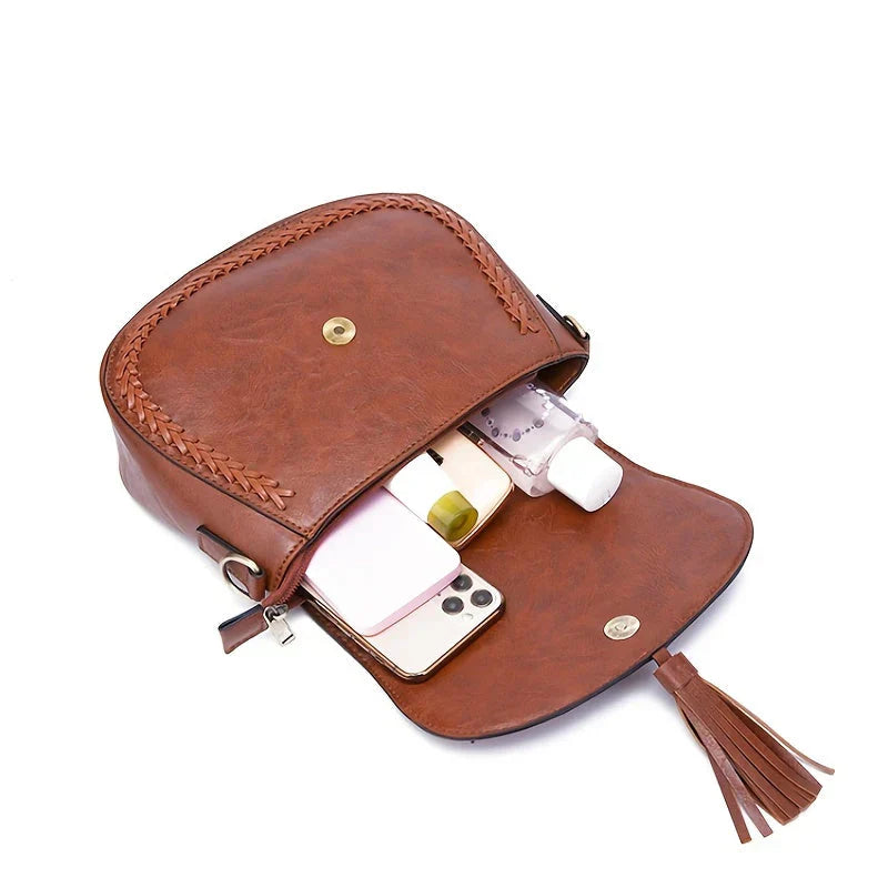 Women's elegant crossbody purse: a versatile saddle bag with a secure flap closure and decorative tassels.