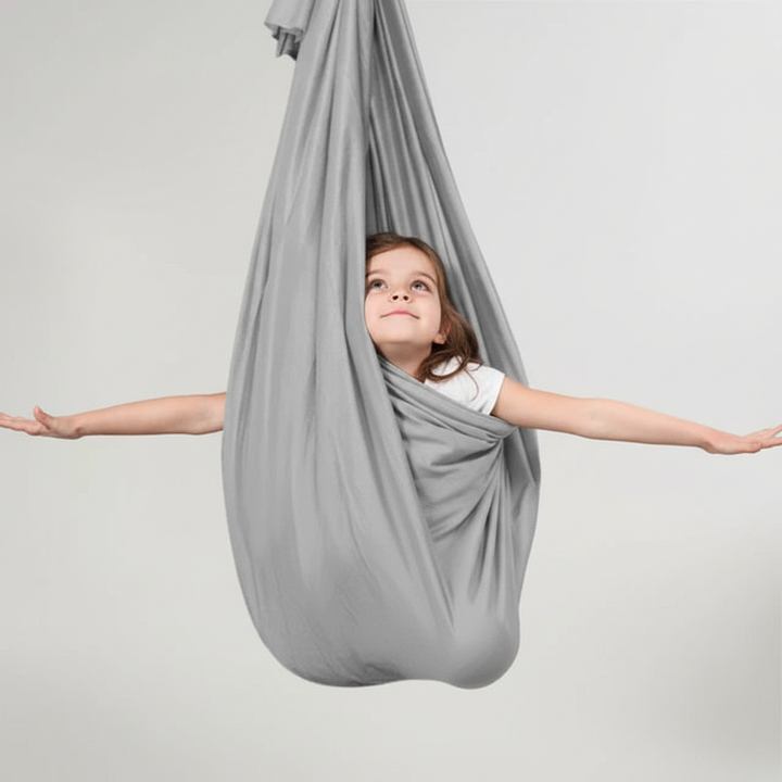 Child actively engaged in an orange sensory swing, enhancing focus and providing relaxation for kids.