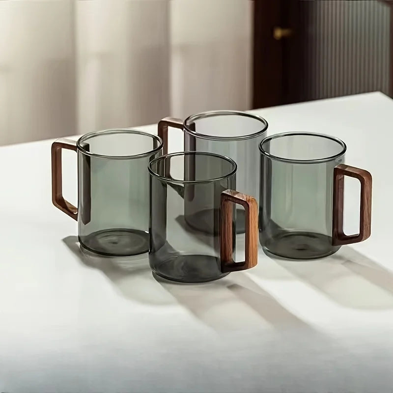 Clear borosilicate glass mug with ergonomic wood handle, perfect for tea or coffee enjoyment.