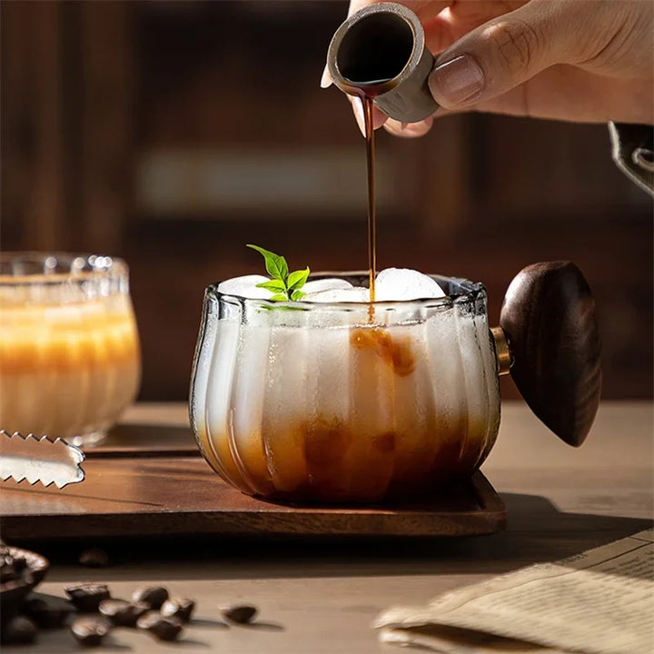 Clear borosilicate glass mug with stylish wooden handle, perfect for hot coffee or cold tea.