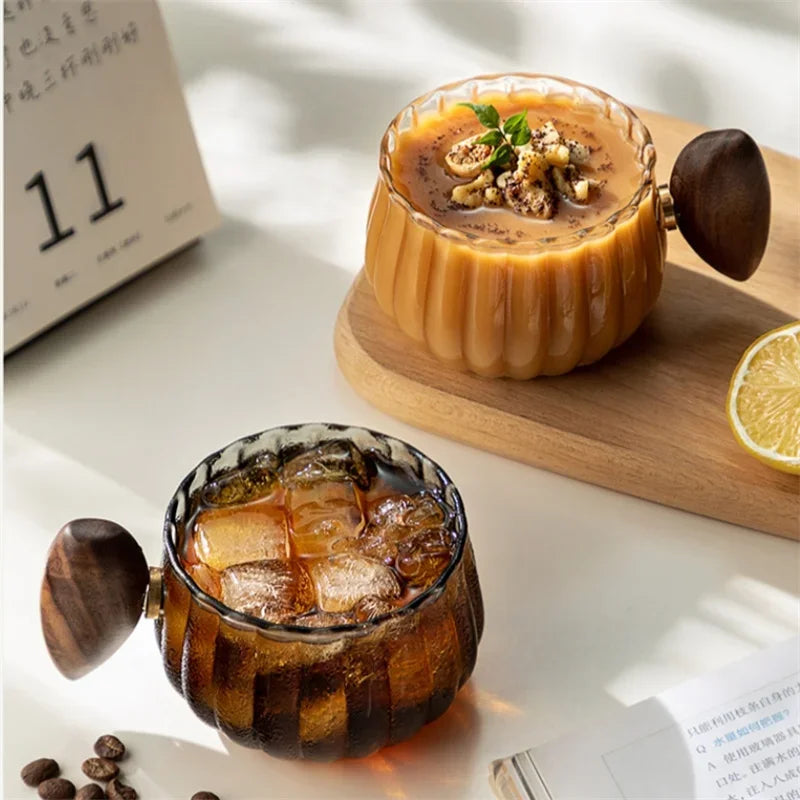 Elegant borosilicate glass coffee mug with comfortable wooden handle; great for modern kitchenware.