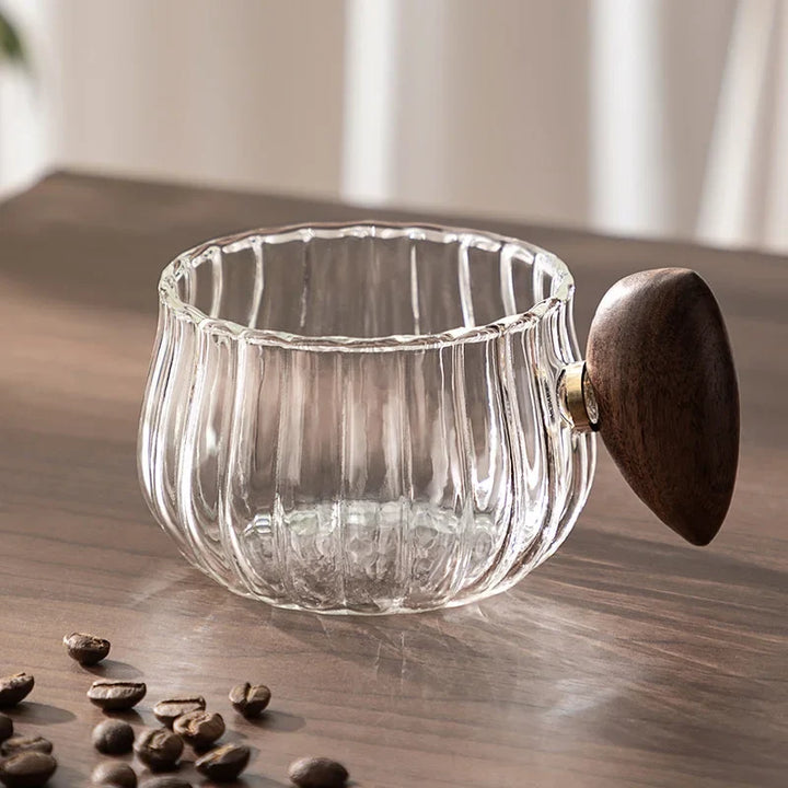 Transparent glass tea cup with wood handle, perfect for enjoying hot herbal tea or cold brew.