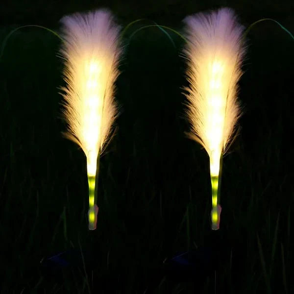 Multiple reed-style solar lights integrated into garden landscaping for ambiance.