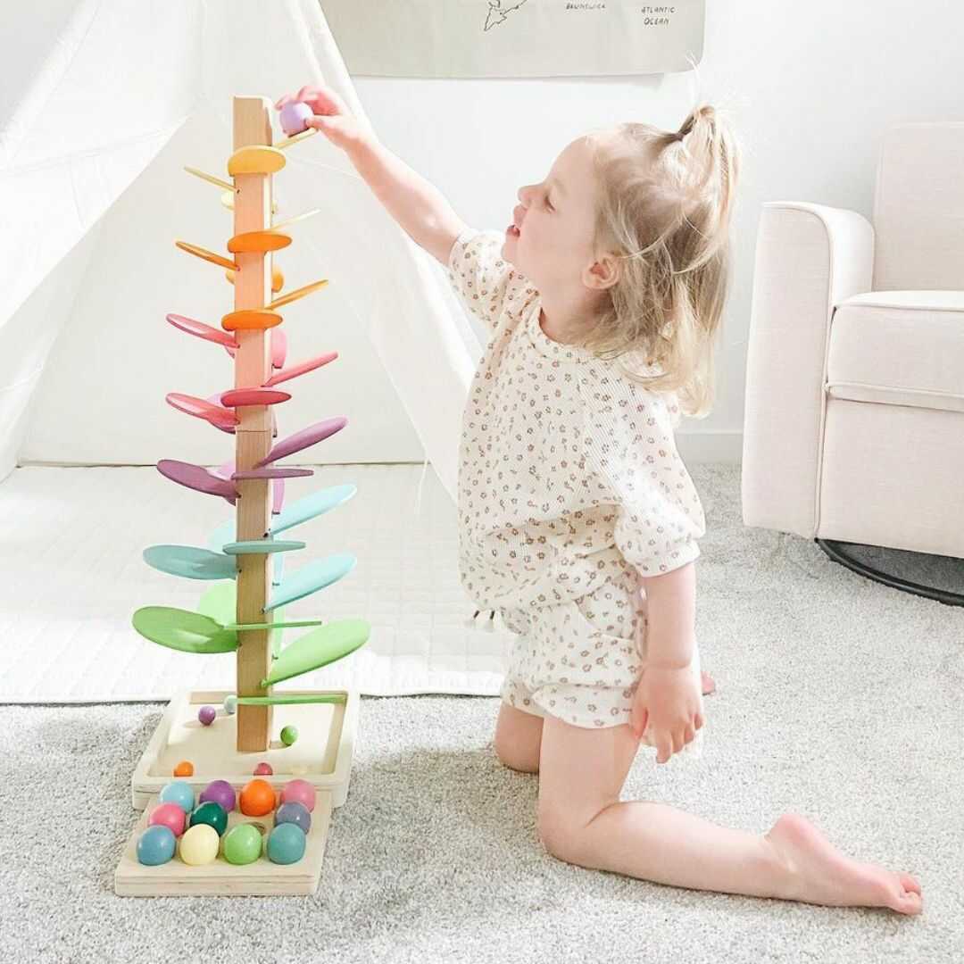 Kids' interactive rainbow marble run tree, a wooden educational toy promoting cause & effect learning & auditory skills.