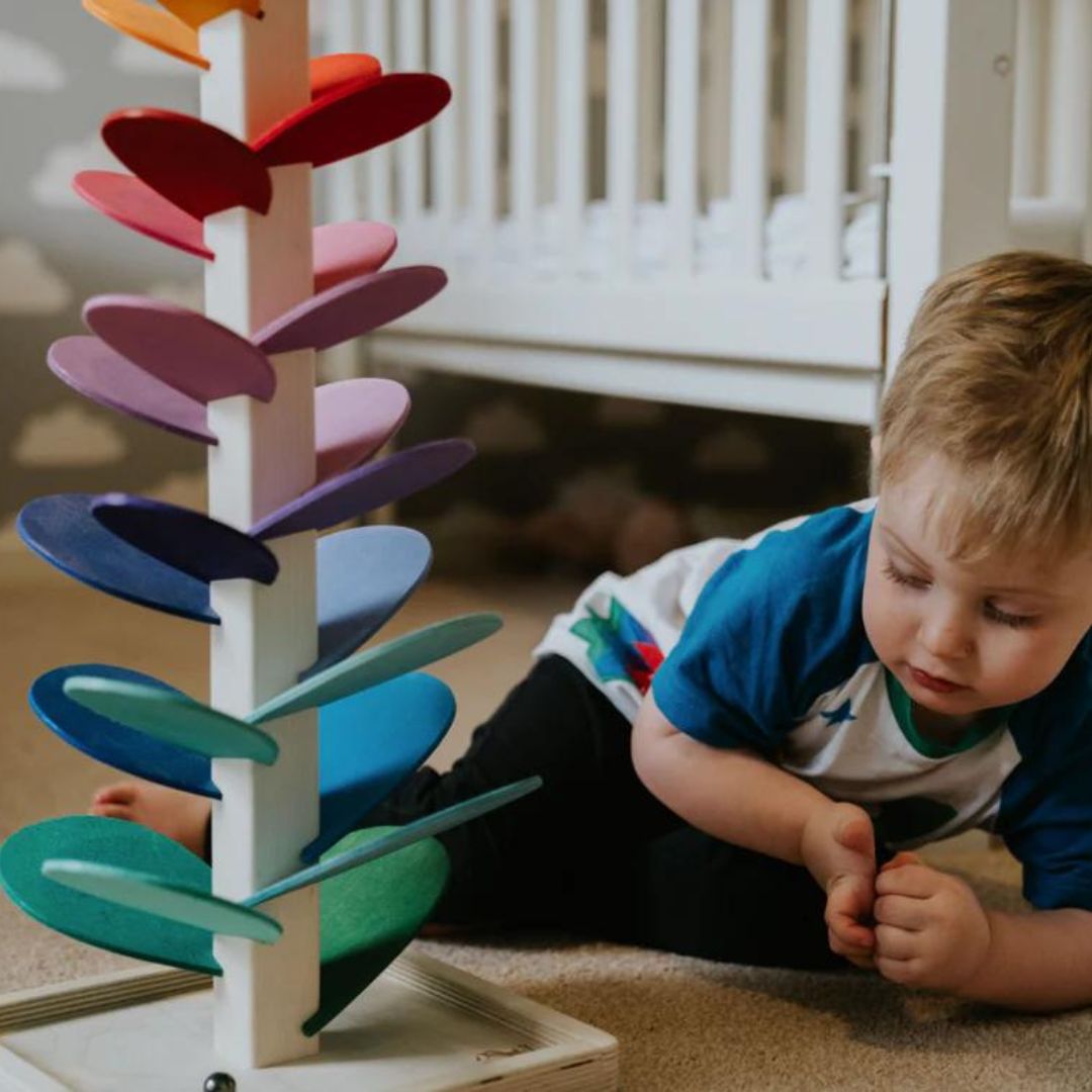 Close-up of a colorful wooden rainbow marble sound tree, showing intricate tracks, vibrant leaves & rolling marbles.