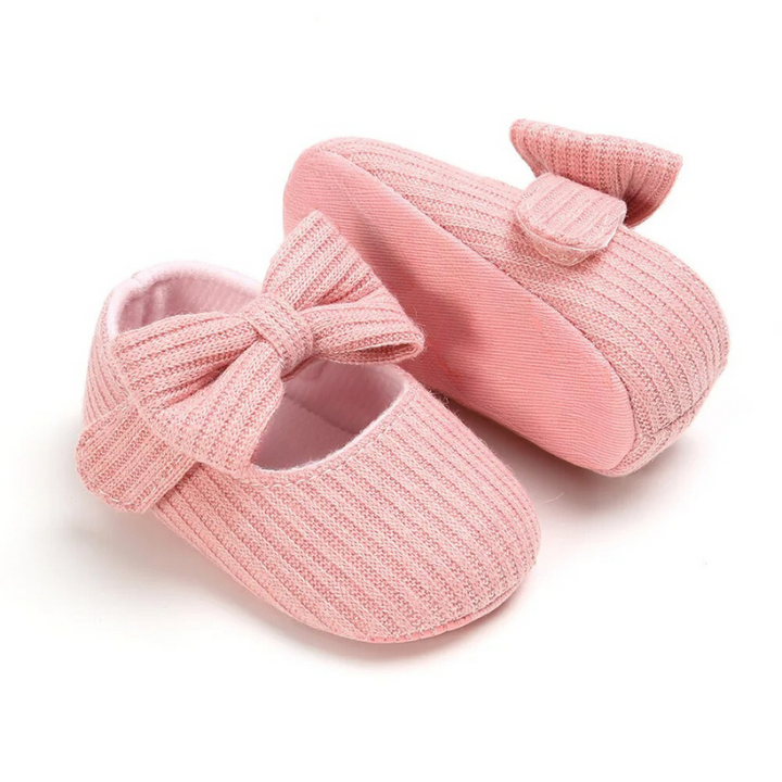 Pair of gender-neutral baby first step shoes displayed, showcasing soft sole & playful design for infants.