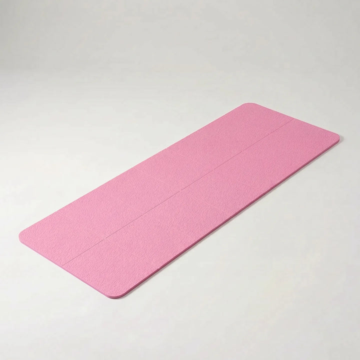 Compact folded travel yoga mat next to a water bottle, emphasizing its portability for fitness, yoga & pilates.