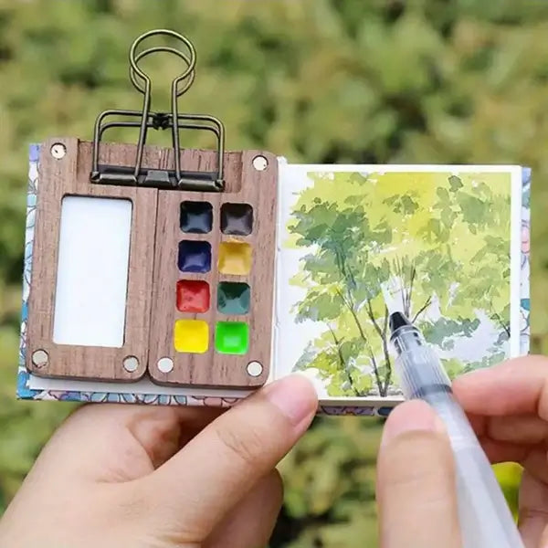 Creative art supplies: compact watercolour set featuring pans, brush, and mixing palette for artists.