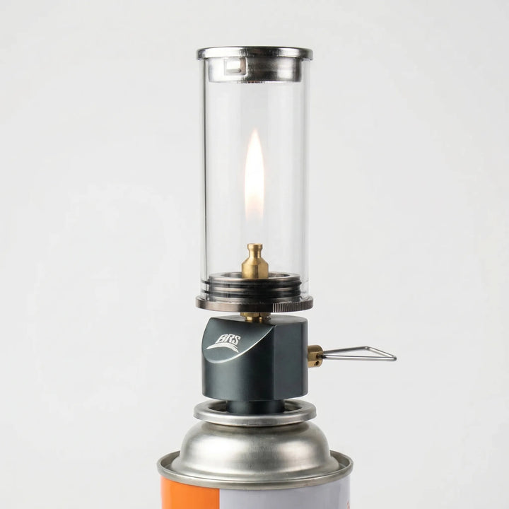 Compact windproof gas camping lamp providing warm candle-like glow for outdoor ambiance & tent lighting.
