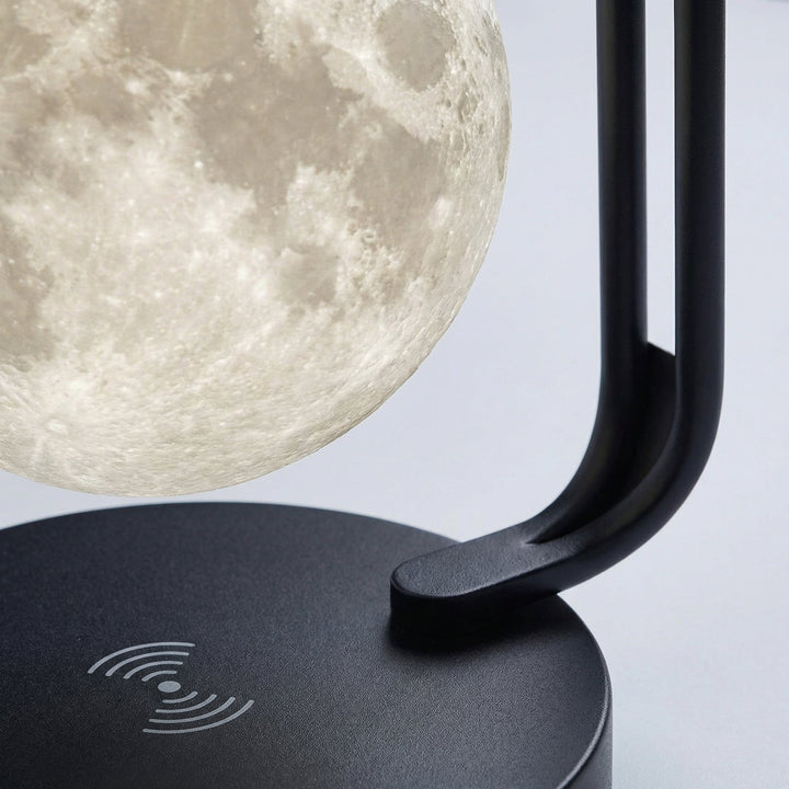 Elegant bedside lamp: cordless, featuring a levitating moon and built-in wireless charging pad.