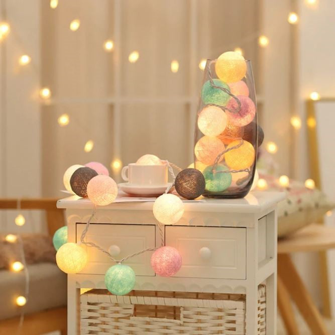 Warm white cotton ball string lights, casting a soft glow, perfect for cozy indoor mood lighting.