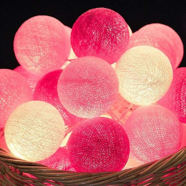 Cotton ball string lights draped over a bed, creating cozy, romantic ambient room lighting.