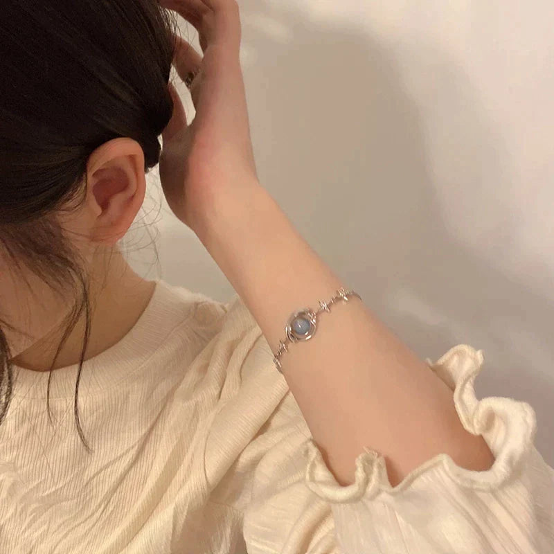 Woman's wrist wearing an elegant dainty celestial charm bracelet, sparkling with cosmic stars & moons. Adjustable women's accessory.