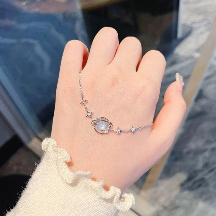 Close-up of a dainty women's celestial charm bracelet, showcasing intricate star & moon charms. Elegant and adjustable jewelry.