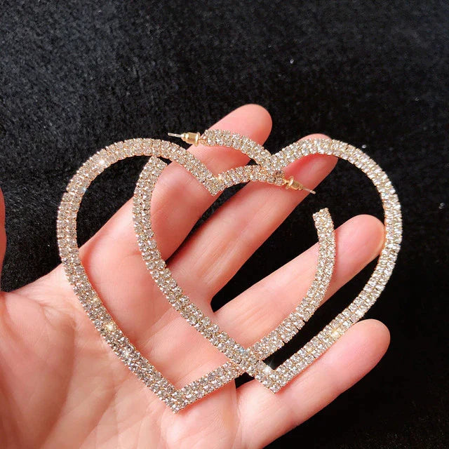 A woman wearing sparkling large crystal heart earrings, adding dazzling elegance to her outfit. Fashion jewelry.
