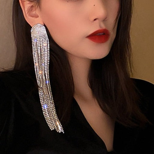 Woman wearing elegant rhinestone tassel drop earrings. Statement party & wedding jewelry for a dazzling look.