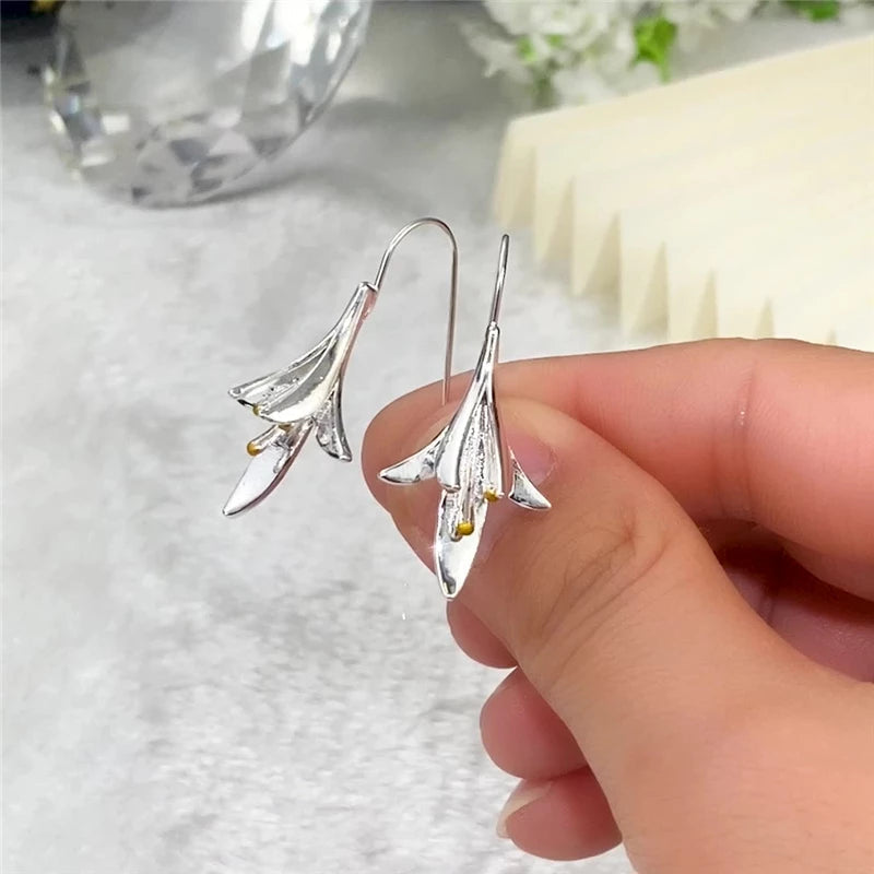 Closeup of women's silver flower petal earrings, highlighting the intricate delicate floral design.