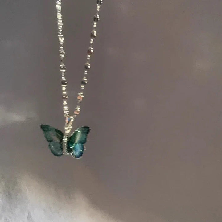 Close-up of a vibrant blue butterfly pendant on a sterling silver chain. A delicate and elegant piece of women's fantasy jewelry.