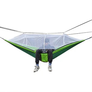 Portable outdoor hammock with bug net suspended between trees, ready for a camping adventure.