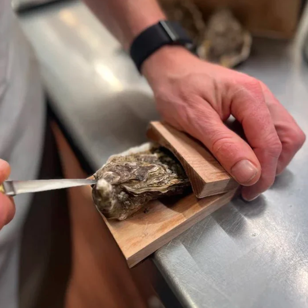 Effortless oyster shucking clamp for safe seafood prep. Wooden base kitchen gadget, holds oysters securely.